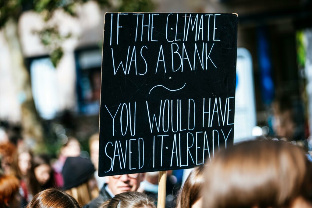 Protesters hold signs at a climate change rally, urging action.